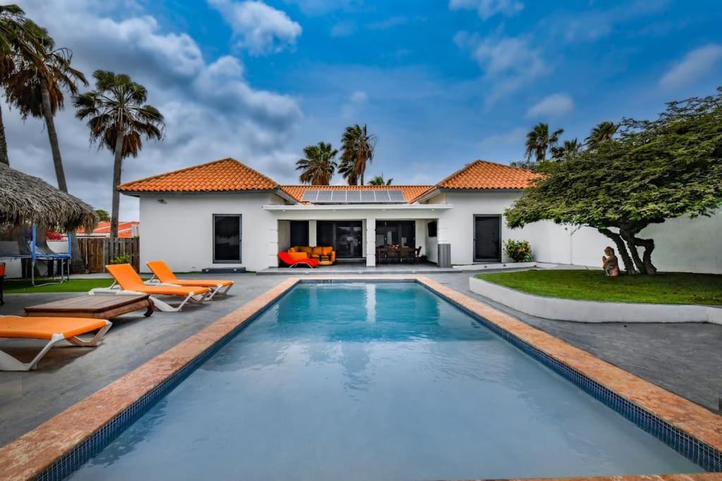 a swimming pool in front of a house with palm trees at 5 bedroom Villa Nune soul beach festival special in Paradera