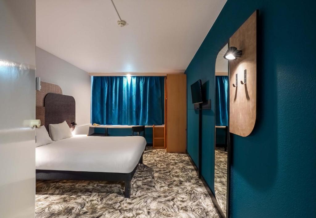 1 dormitorio con cama y pared azul en B&B HOTEL Chartres Centre Cathédrale en Chartres
