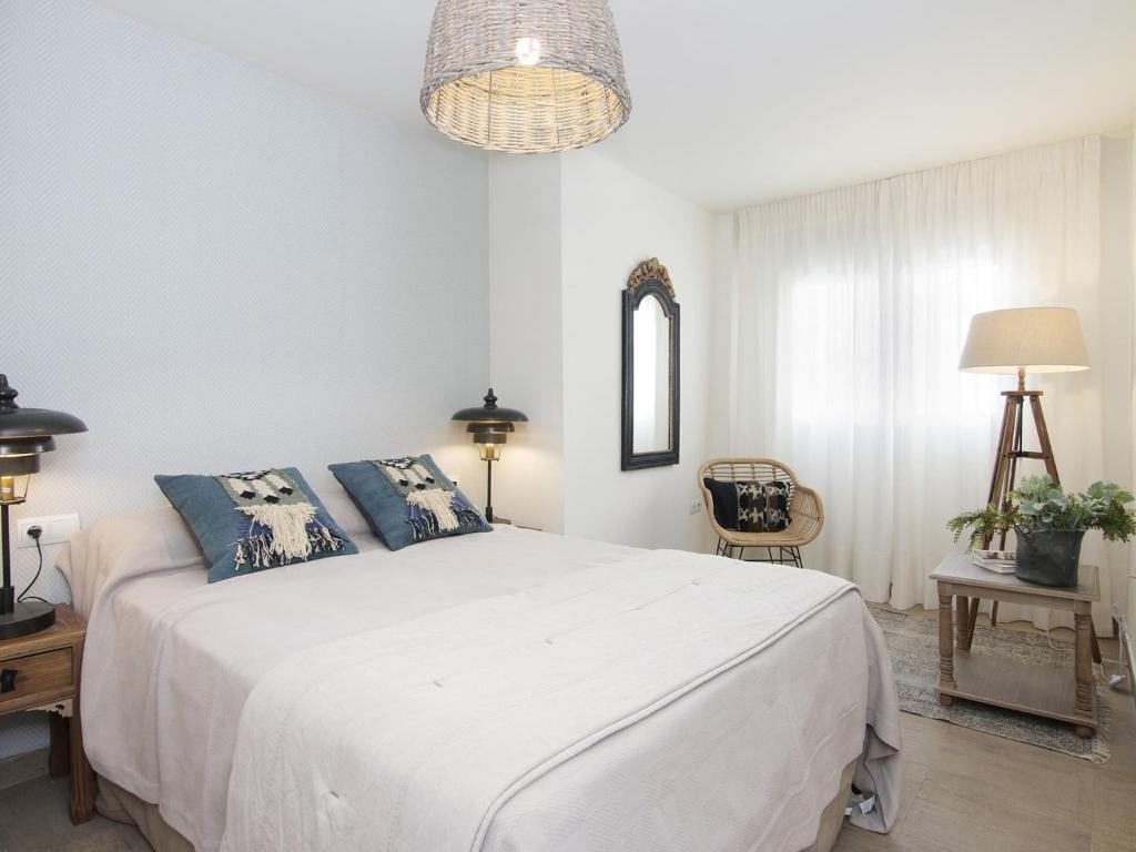 a bedroom with a large white bed with blue pillows at Chezmoihomes Apartment Cathedral 2 dormitorios in Granada