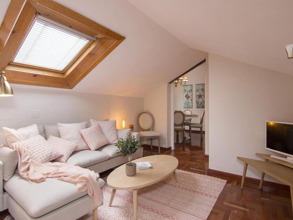Chezmoihomes Alhambra Penthouse في غرناطة: غرفة معيشة مع أريكة بيضاء وتلفزيون