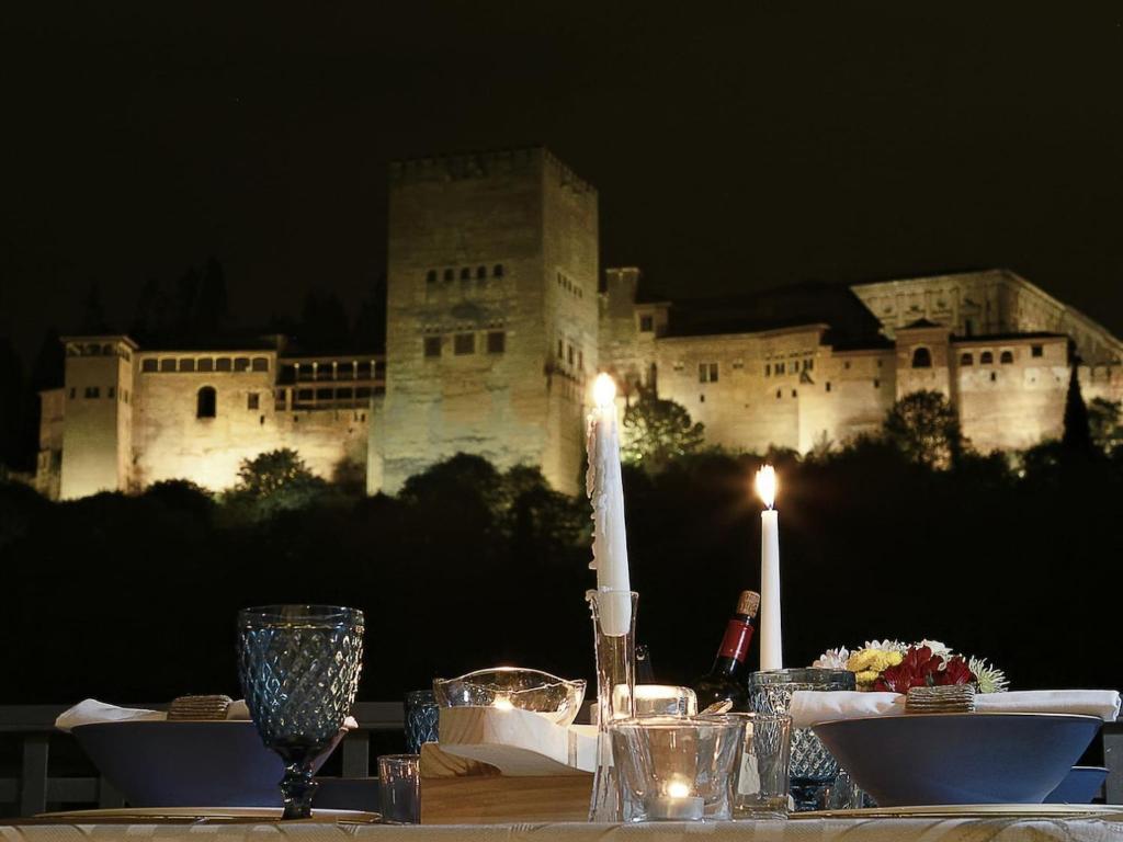 a table with candles and a castle in the background at Chezmoihomes Alhambra Penthouse 2 private terraces in Granada