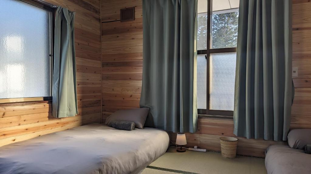 a bedroom with two beds in a wooden room with windows at Yukiumi Furano in Furano