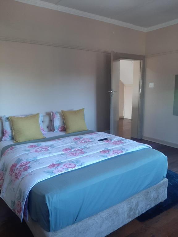a bedroom with a large bed with a blue comforter at triple S guest house in Cape Town