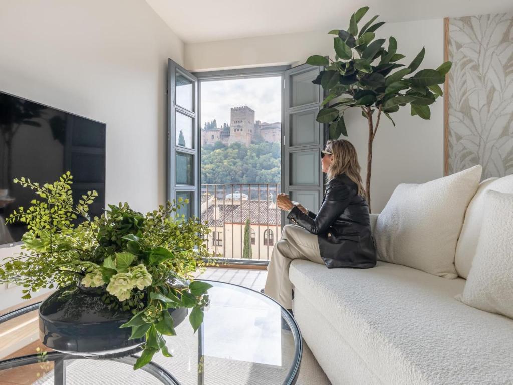 a woman sitting on a couch looking out a window at Alhambra Dream in Granada