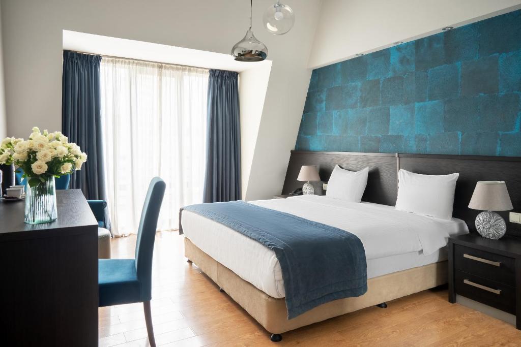 - une chambre avec un lit et un mur bleu dans l'établissement Sephia Hotel, à Tbilissi