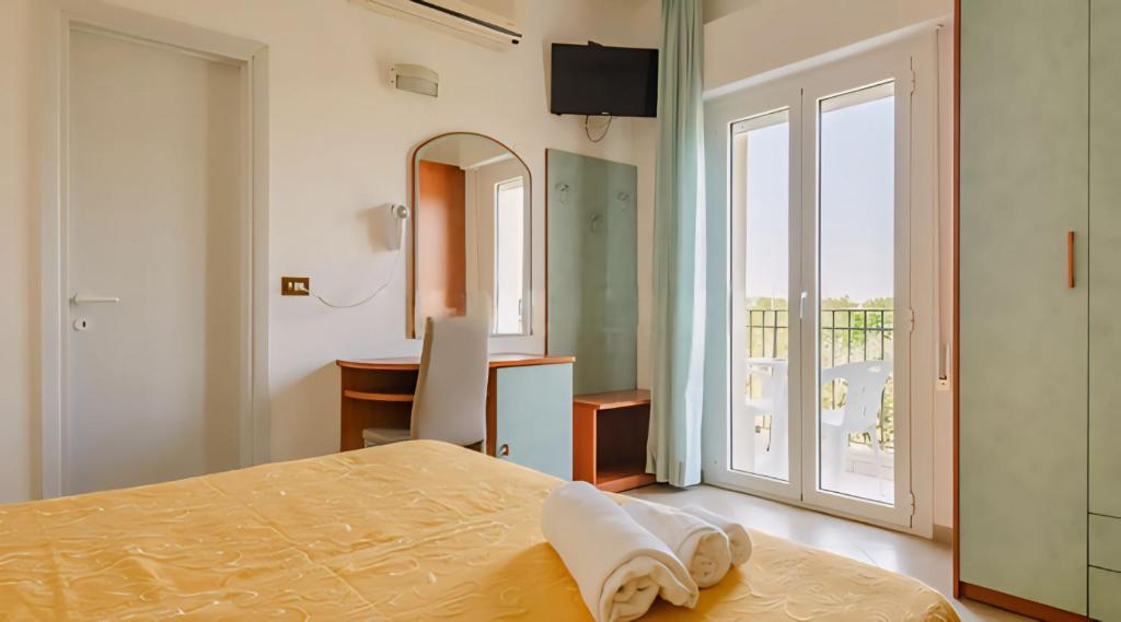 a bedroom with a bed and a desk and a window at Hotel Baltic in Misano Adriatico