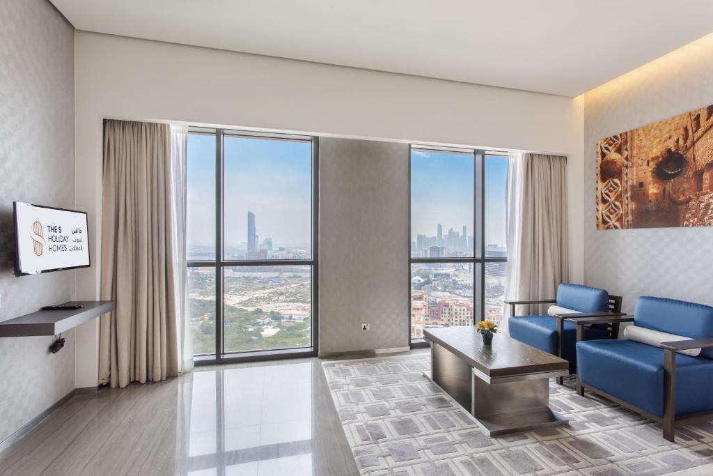 een woonkamer met blauwe stoelen en een groot raam bij Spacious Studio Apartment in Hyatt Regency Dubai Creek Heights by the S Holiday Homes in Dubai