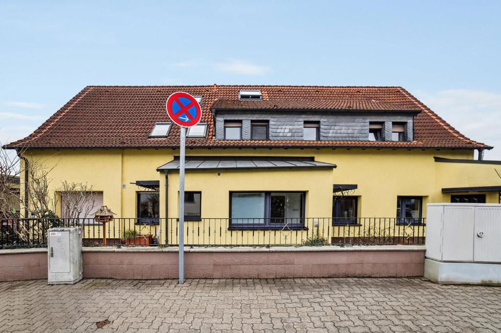 une maison jaune avec un panneau de rue devant elle dans l'établissement Nice Apartments in Hanau, à Hanau