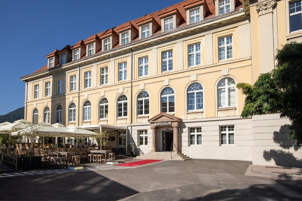 a large building with tables and chairs in front of it at Hotel Böhlerstern in Kapfenberg