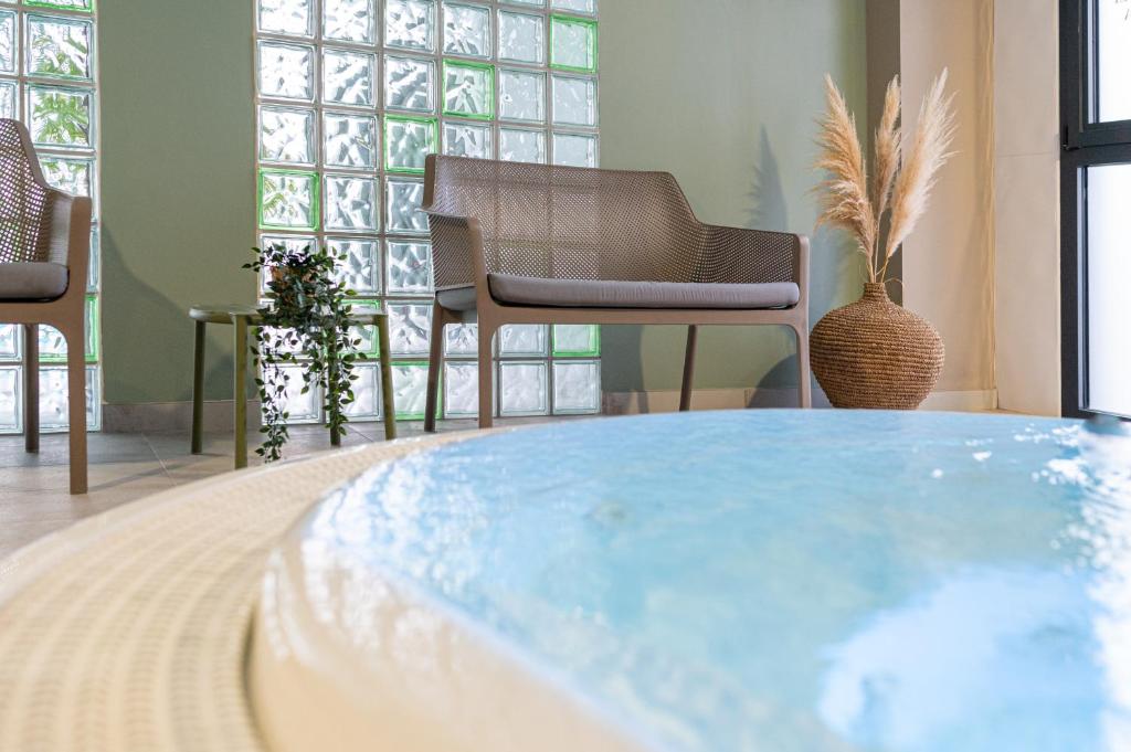 a hot tub in a room with chairs and windows at Kyriad Prestige Residence & Spa Cabourg-Dives-sur-Mer in Dives-sur-Mer