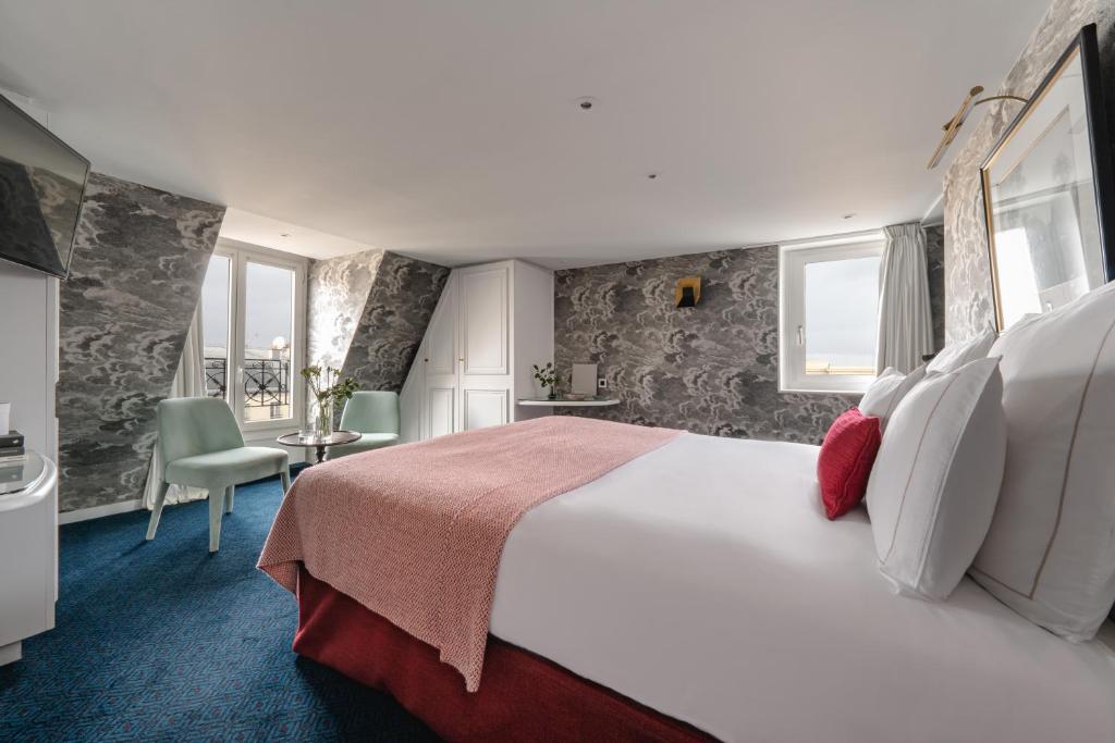 una habitación de hotel con una gran cama blanca y ventanas en Hôtel Bourgogne & Montana, en París