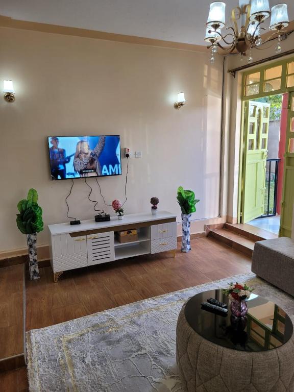 a living room with a flat screen tv on a wall at Gloria House in Nairobi