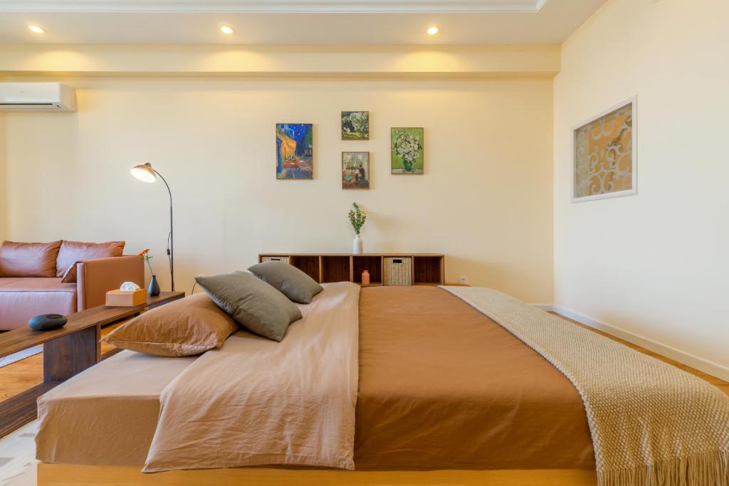 a bedroom with a large bed and a couch at Dalian Baobab Apartment in Dalian