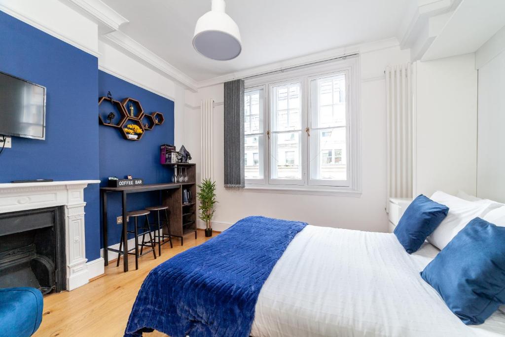 a blue and white bedroom with a bed and a fireplace at Cannon Street Studios in London