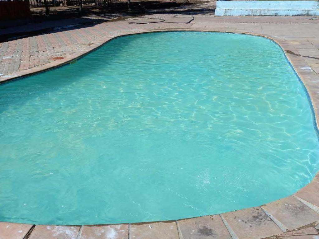 una piscina de agua azul en un patio en @ The Village Lodge, en Hazyview
