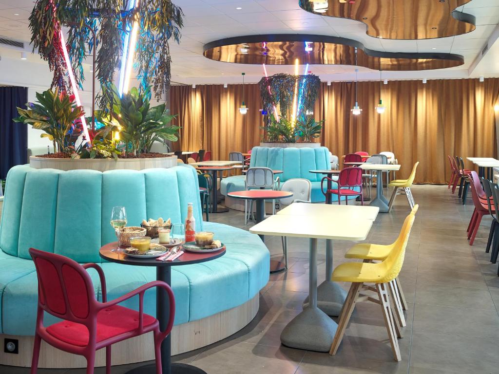 パリにあるB&B HOTEL Paris 17 Batignollesのカラフルな椅子とテーブルが備わるレストラン