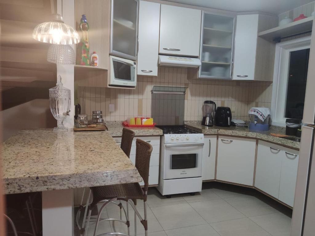 a kitchen with white cabinets and a counter top at Casa em Arraial d’Ajuda in Porto Seguro