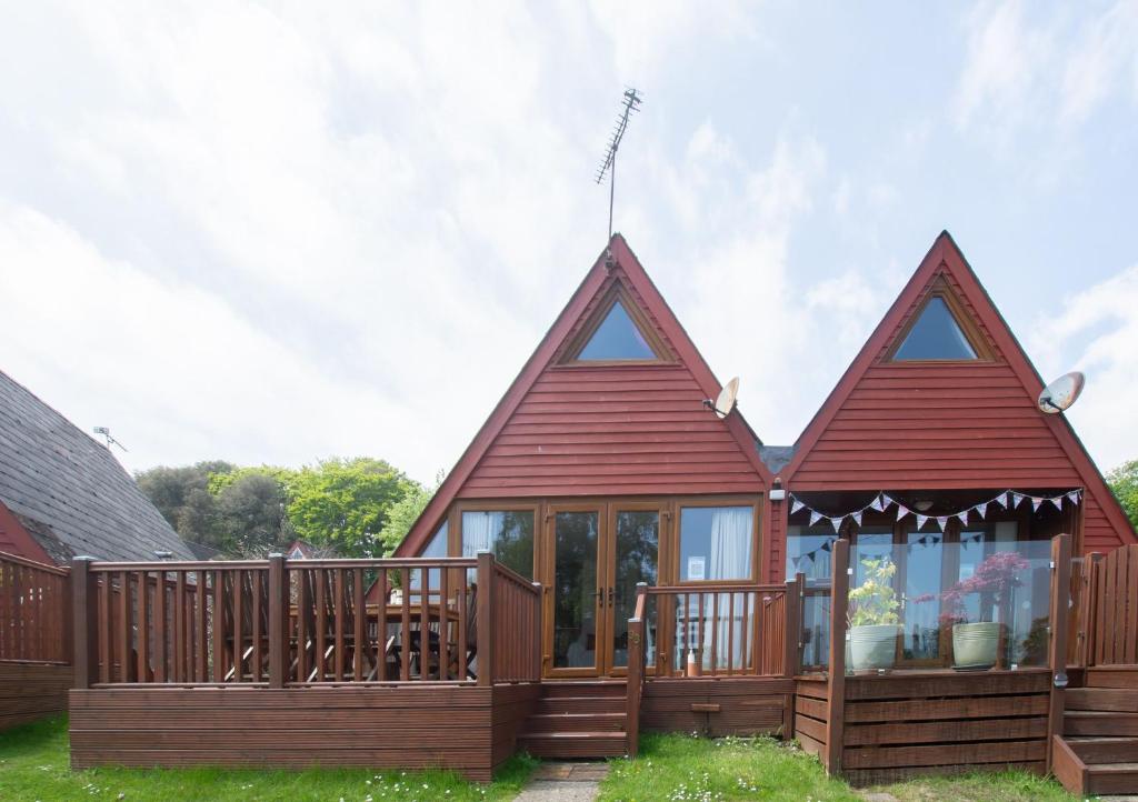 a large red house with a deck and windows at Chalet 98 in Deal