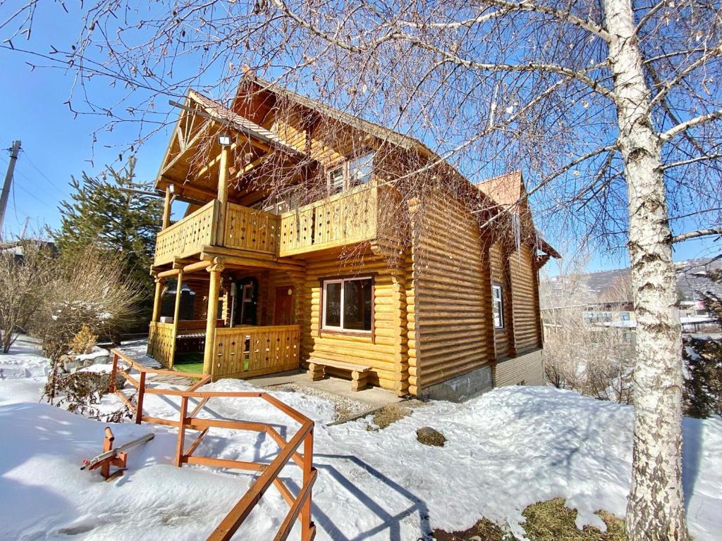 una cabaña de madera en la nieve con un árbol en Сакский Двор en Besqaynar