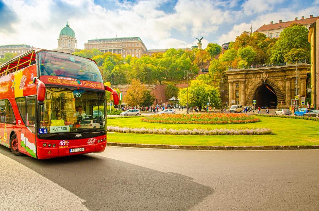 a red double decker bus driving down a street at Skylark Cozy Bigger Apartment in Budapest