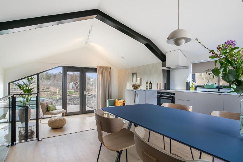 uma cozinha em plano aberto e sala de jantar com uma mesa azul em Waterlinie Lodges em Utrecht