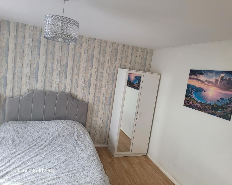 a bedroom with a bed and a mirror and a chandelier at Homely place in Theale