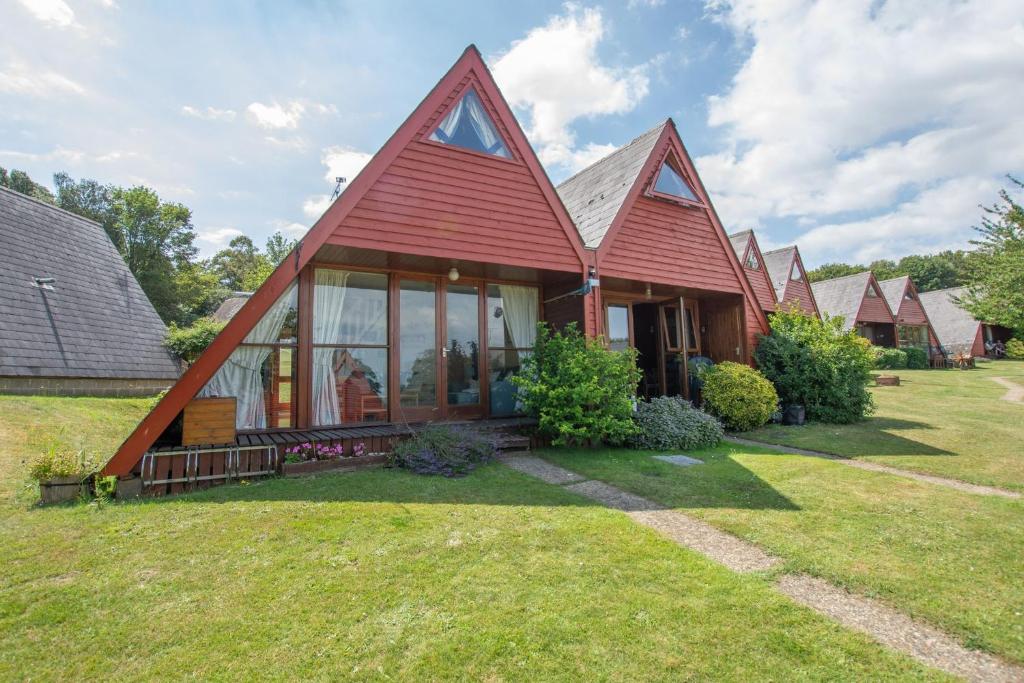 a house with a red roof on a yard at Chalet 106 in Deal