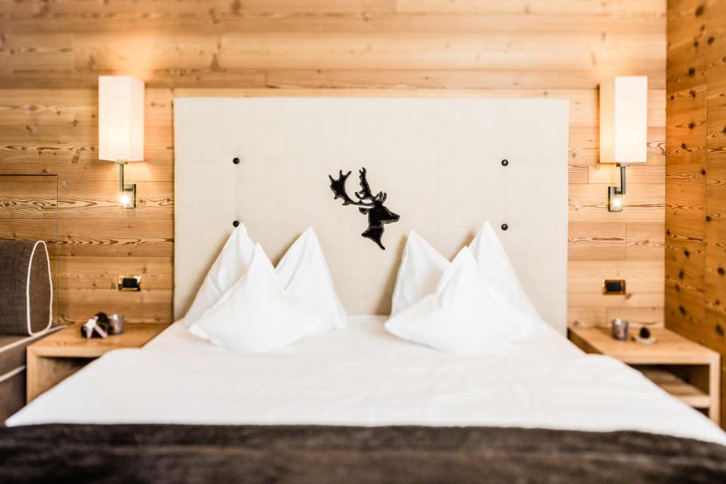 セルヴァ・ディ・ヴァル・ガルデーナにあるホテル ドルファー アルパイン＆チャーミングのベッドルーム(白い枕のベッド1台付)
