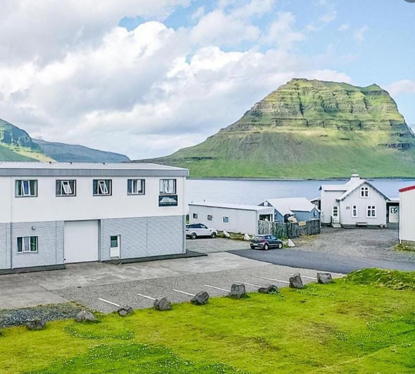 a large white building with a mountain in the background at Stöð Guesthouse and apartments in Grundarfjordur