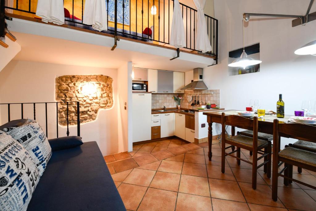 a kitchen and living room with a table and a dining room at Appartamento Porticciolo in Gargnano