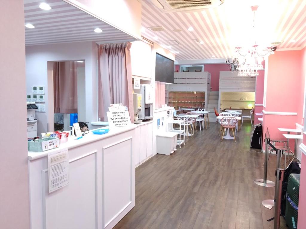 eine Küche mit weißen Arbeitsflächen und ein Esszimmer mit Tischen in der Unterkunft Cafe&Hostel きみといちご in Osaka