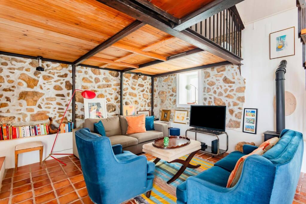 a living room with a couch and a tv at Casalinho de Bicesse in Alcabideche