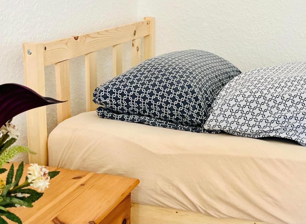 ein Bett mit blauen und weißen Kissen und einem Holztisch in der Unterkunft Zimmer in Werneuchen bei Berlin in Werneuchen