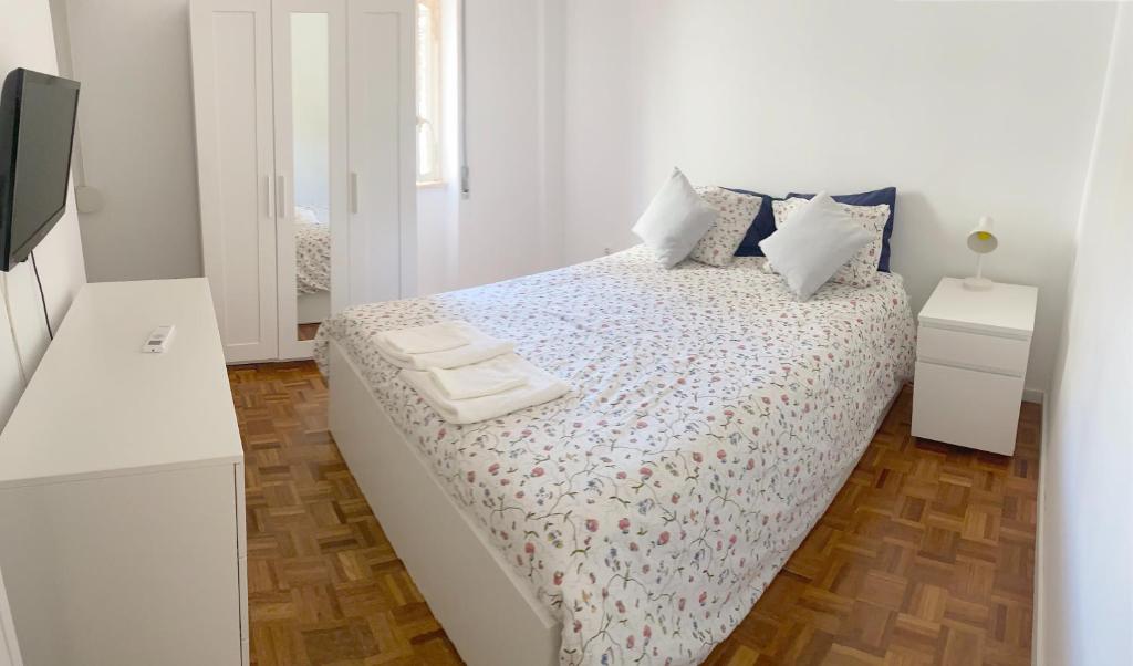 ein weißes Schlafzimmer mit einem Bett mit zwei Handtüchern darauf in der Unterkunft Estoril 2 bedrooms by the Beach in Estoril