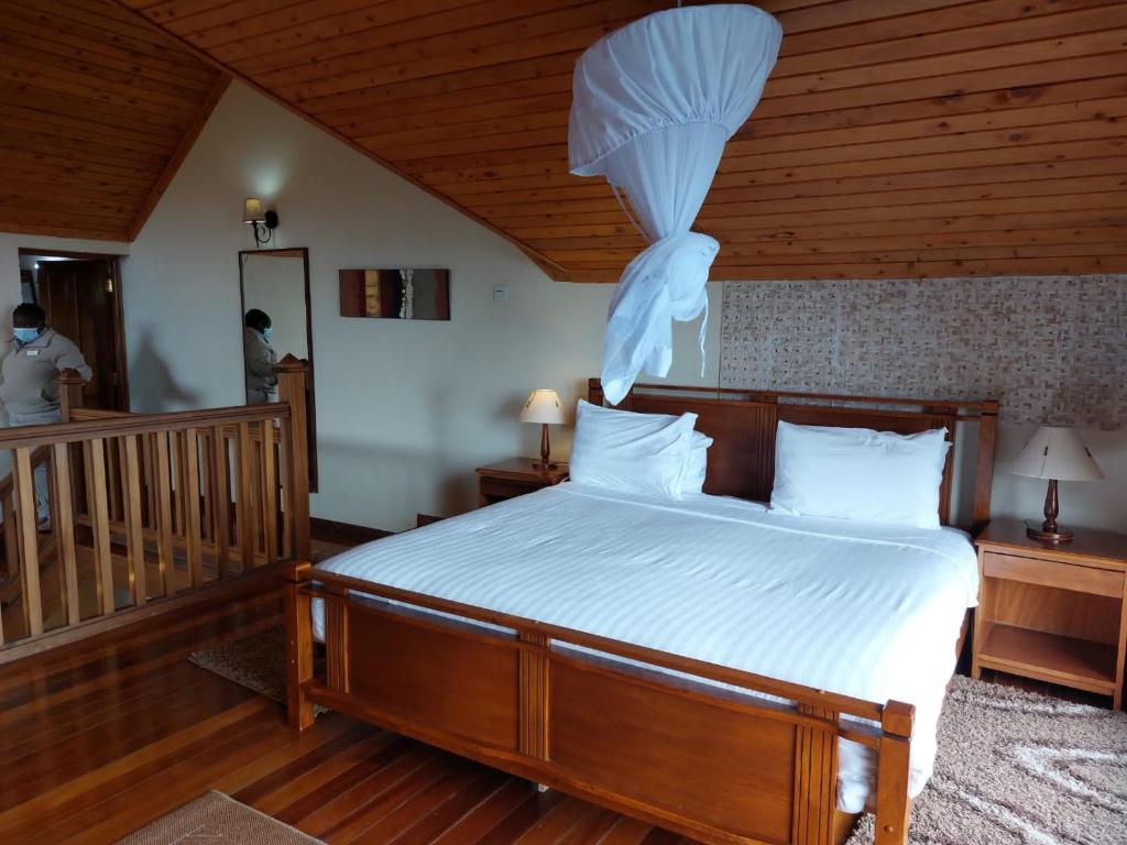 una camera da letto con un letto con lenzuola bianche e un soffitto in legno di Great Rift Valley Lodge and Golf Resort a Naivasha