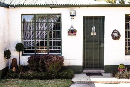 a white house with a black door at Clifford Selfcatering Guesthouse in Barkly East