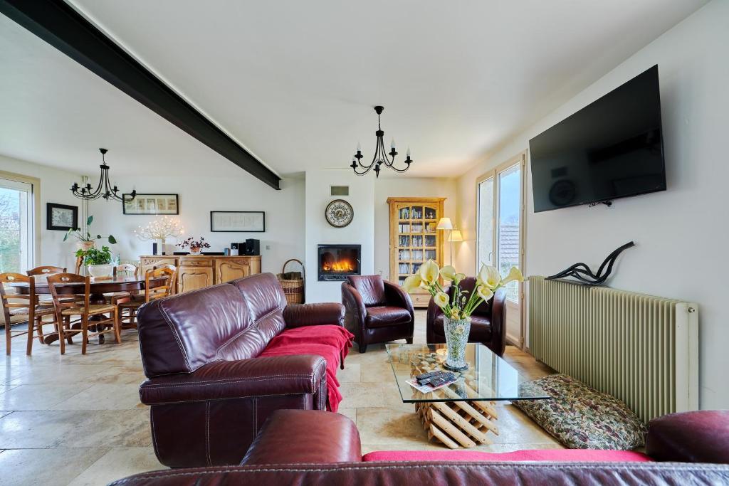 sala de estar con muebles de cuero y comedor en Maison Boisée - Charmante maison au calme 