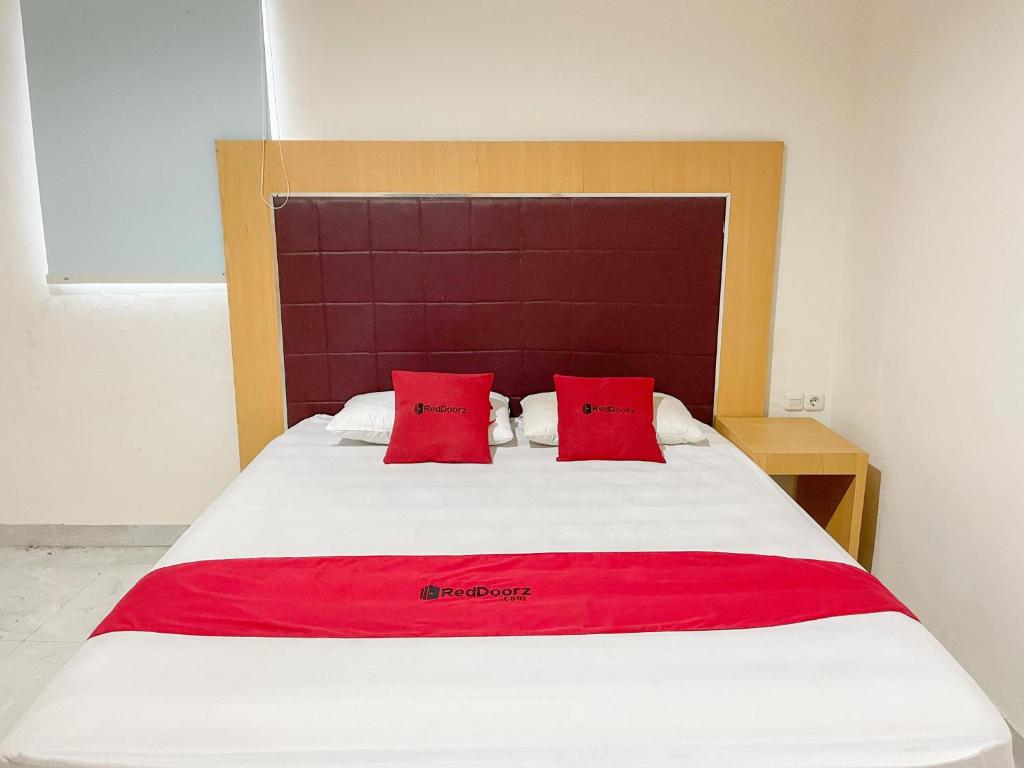 MandaiにあるRedDoorz @ Wisma Graha Andi Djemmaの大型ベッド(赤い枕2つ付)