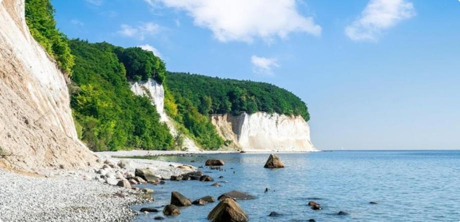 einen Strand mit Felsen im Wasser neben einem Berg in der Unterkunft Ferienwohnung in Sassnitz RÜGEN Nähe Weltnaturerbe Kreideküste in Sassnitz