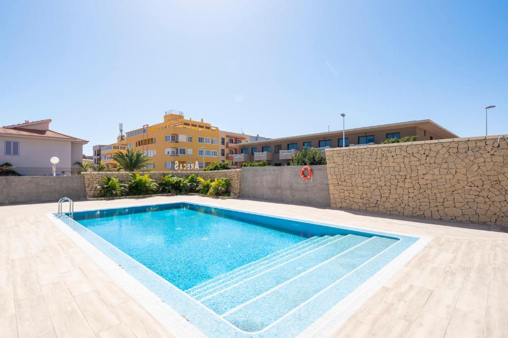 a swimming pool in front of a building at MEDANO4YOU Arecas Del Mar in El Médano