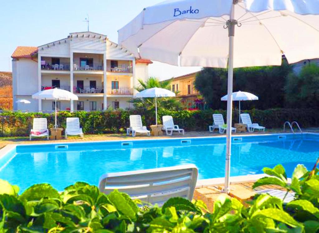 a swimming pool with chairs and umbrellas and a building at Barko Apartments & Suites in Steccato