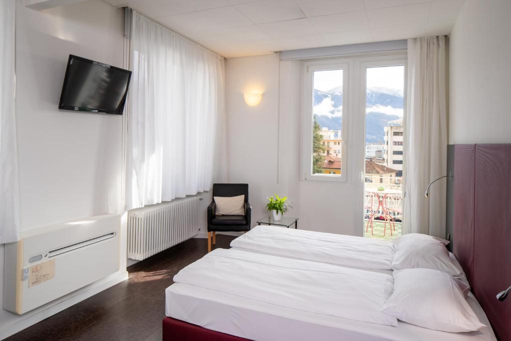 um quarto com uma cama branca e uma janela em Hotel Rio Muralto em Locarno