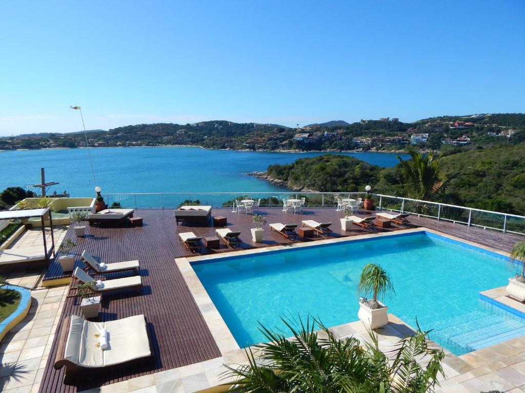 a swimming pool with chairs and a view of the water at Uni Boutique Hotel & Spa in Búzios