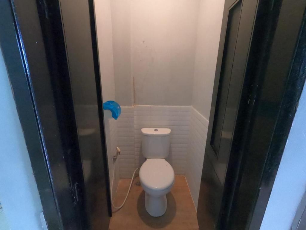 a small bathroom with a white toilet in a stall at Innbox Hostel in Sorong