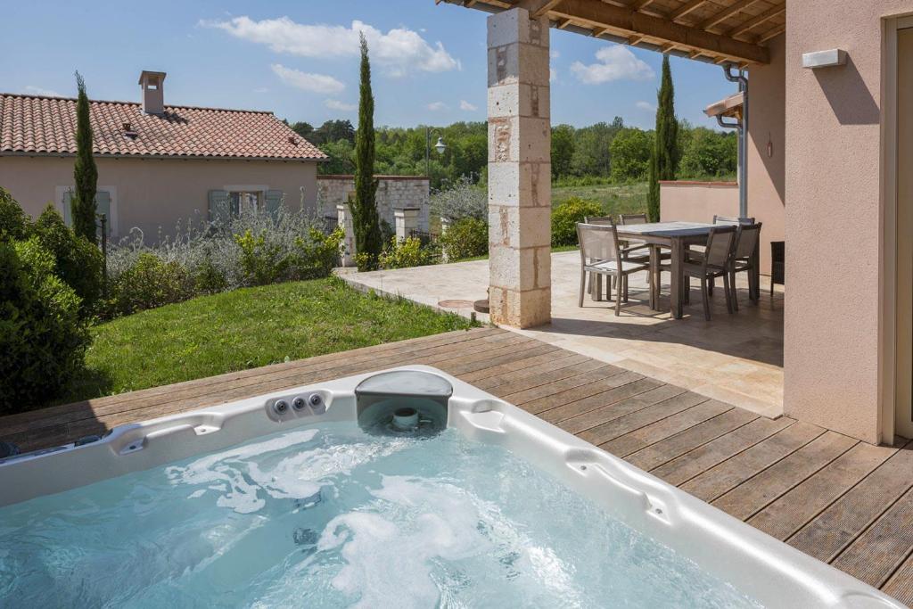 una vasca idromassaggio in un cortile con tavolo di Domaine de la durantie - villa avec jacuzzi a Castelnau-de-Montmiral