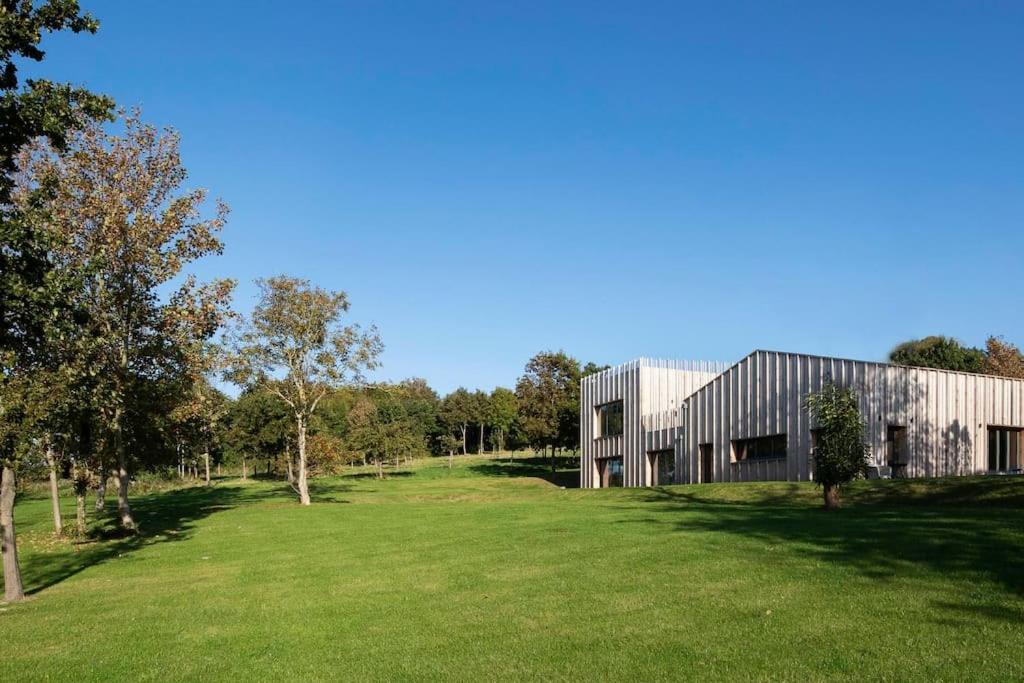 un bâtiment avec un champ herbeux devant lui dans l'établissement Maison face à la mer dans un domaine écologique, à Villerville