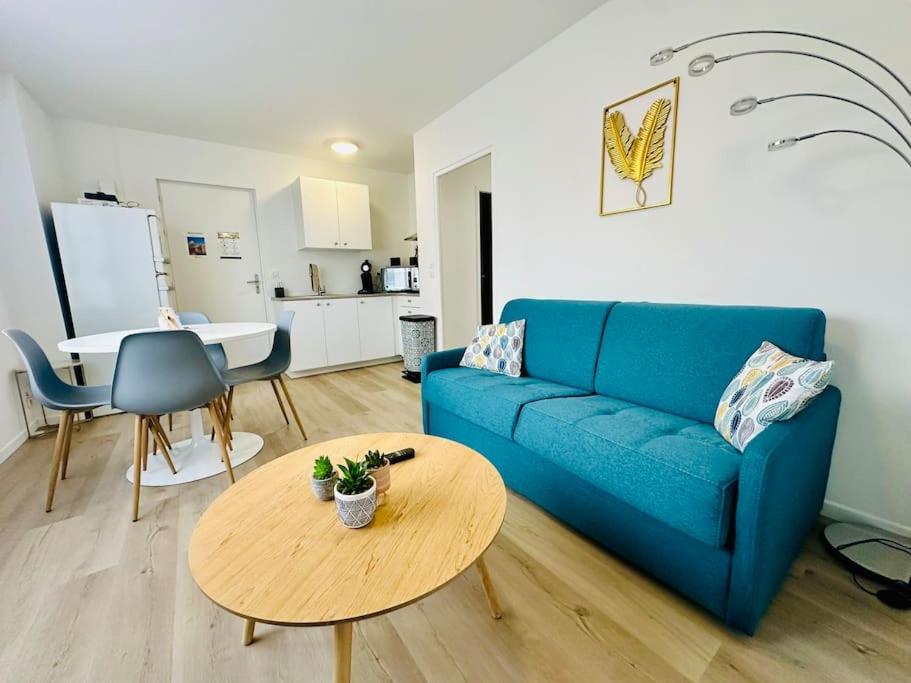 uma sala de estar com um sofá azul e uma mesa em Charmant T2 * proche plage * parking gratuit em La Rochelle