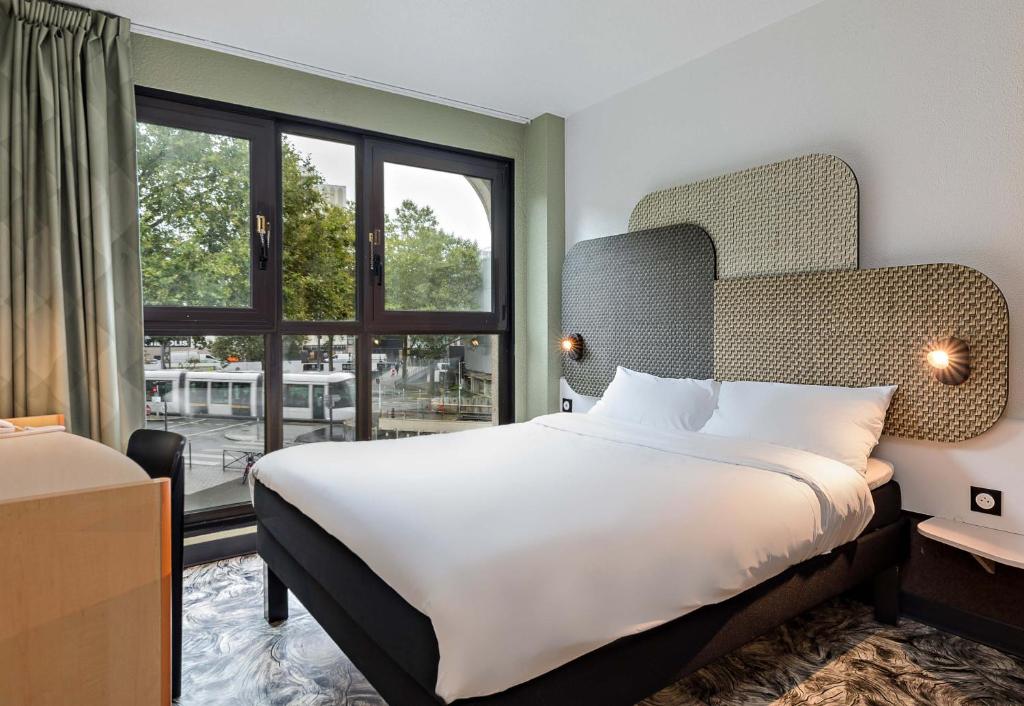 ein Schlafzimmer mit einem großen Bett und einem großen Fenster in der Unterkunft B&B HOTEL Rouen Centre Rive Gauche in Rouen