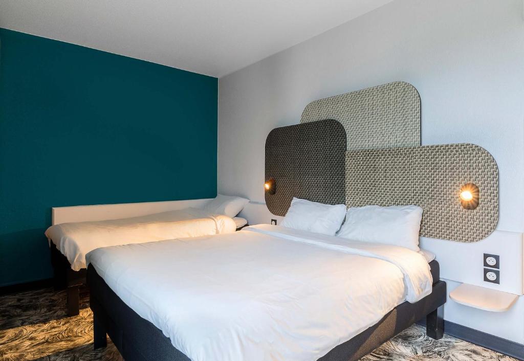 deux lits dans une chambre aux murs verts dans l'établissement B&B HOTEL Rouen Centre Rive Gauche, à Rouen