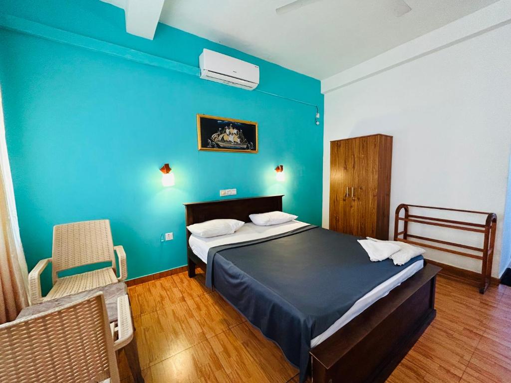 a bedroom with a bed and a blue wall at Ritz Gate Kalutara in Kalutara